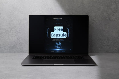 A dark gray laptop sits open on a light gray surface against a textured gray wall, with its screen displaying a digital graphic that reads 'Free Capsule' and the brand name 'TREVOLOX'.
